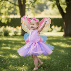 Child in a colorful fairy costume with wings standing on grass